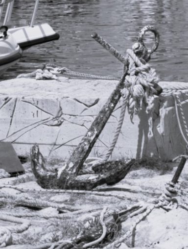 Vieille ancre rouillée, laissée sur le quai au milieu des bouts.
